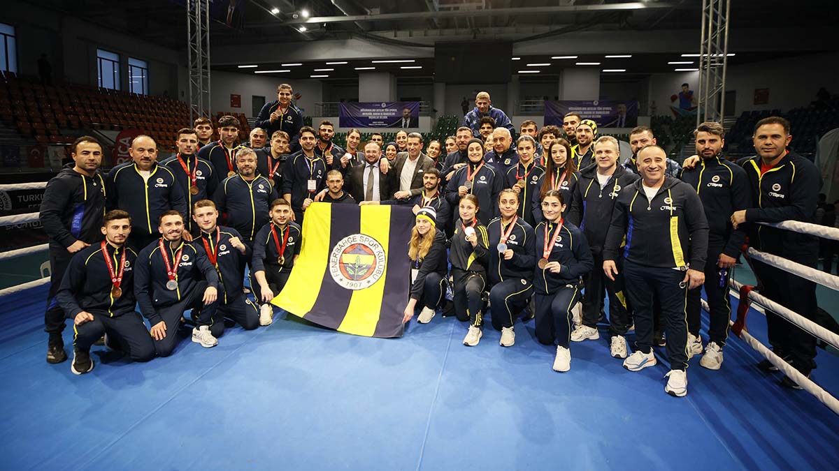 Fenerbahçe Boks Takımı sporcuları ve teknik ekibi ringde, sarı-lacivert bayrakla birlikte poz veriyor